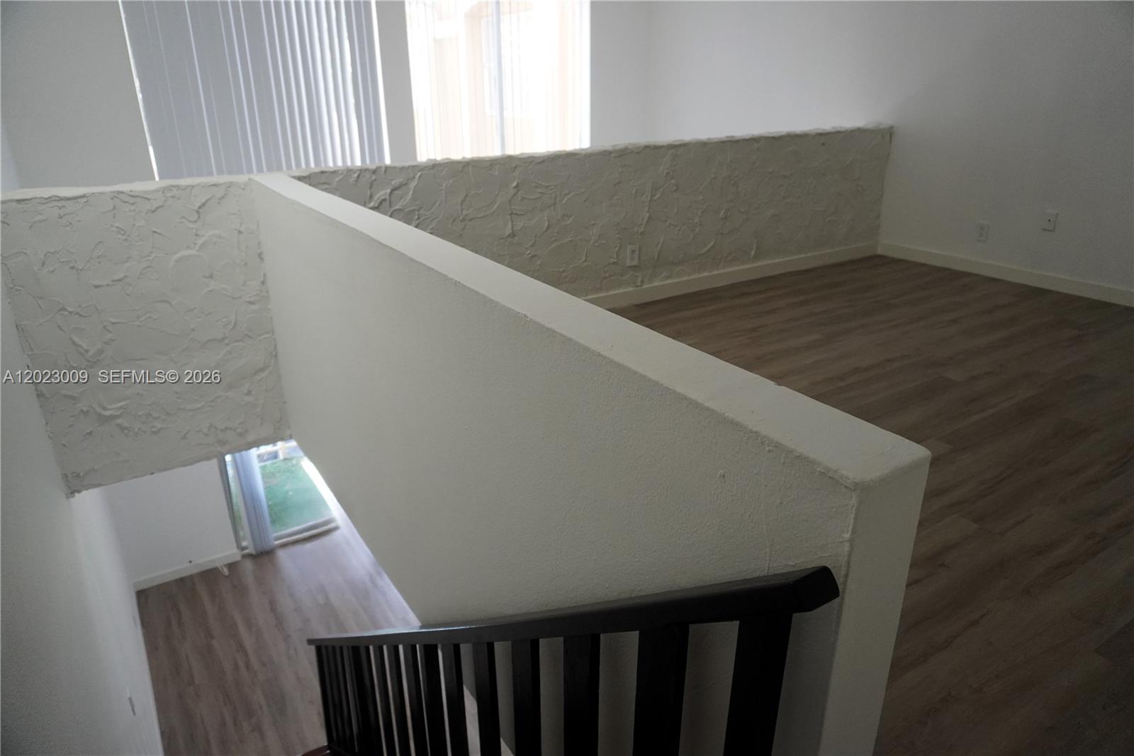 A staircase with a dark railing leads to an upper landing with textured walls — 17901 NW 68th Ave # S204, Hialeah FL 33015, HIALEAH, FL