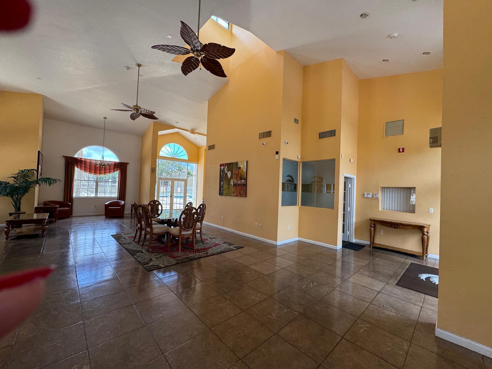 A spacious lobby features high ceilings, tile flooring, a dining area, and yellow walls — 417 E Palm Cir Circle E # 417, Pembroke Pines FL 33025, PEMBROKE PINES, FL