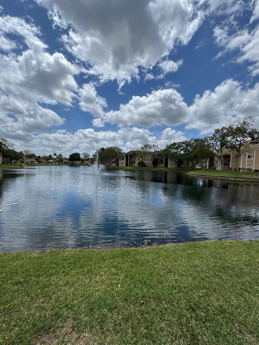 A view of a lake with a fountain in front of multi-story apartment buildings — 417 E Palm Cir Circle E # 417, Pembroke Pines FL 33025, PEMBROKE PINES, FL