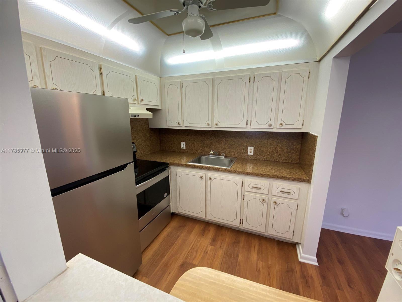 A kitchen features light wood cabinets, granite countertops, stainless steel appliances, and wood-look flooring — 381 Fanshaw J # 381, Boca Raton FL 33434, BOCA RATON, FL