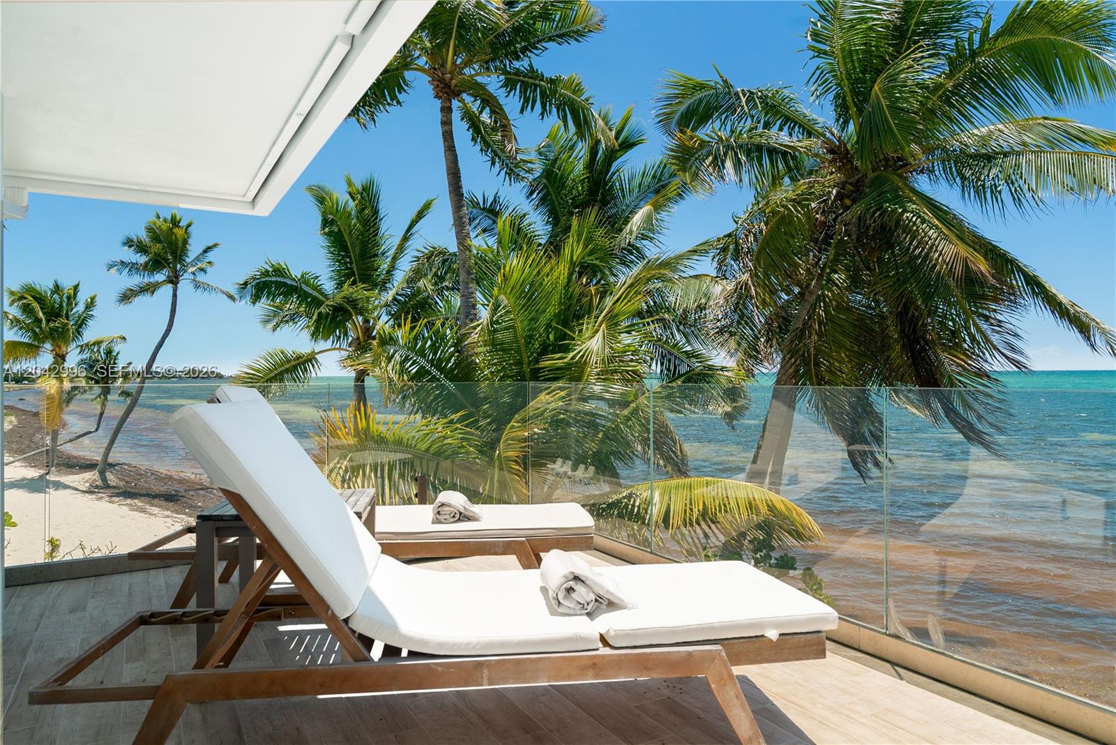 Two lounge chairs sit on a balcony overlooking a beach with palm trees and ocean — 74051 Overseas Hwy, Islamorada FL 33036, ISLAMORADA, FL