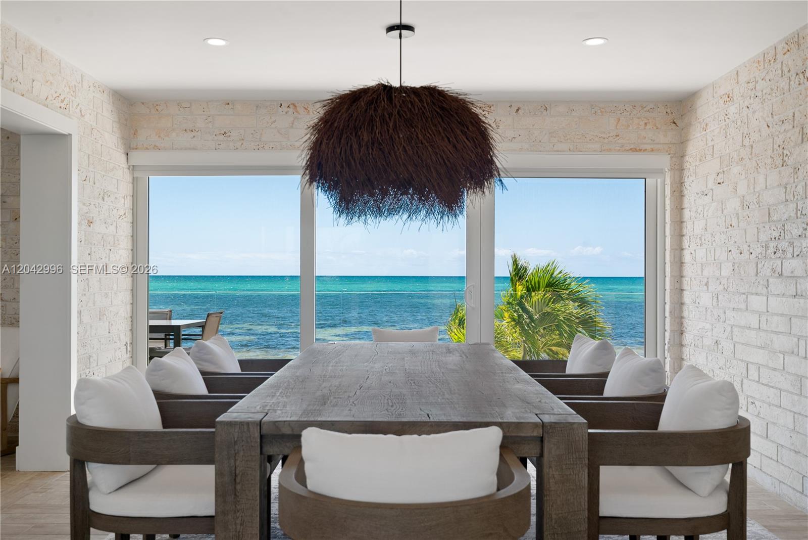 A dining room features a large wooden table, textured pendant light, and ocean views — 74051 Overseas Hwy, Islamorada FL 33036, ISLAMORADA, FL