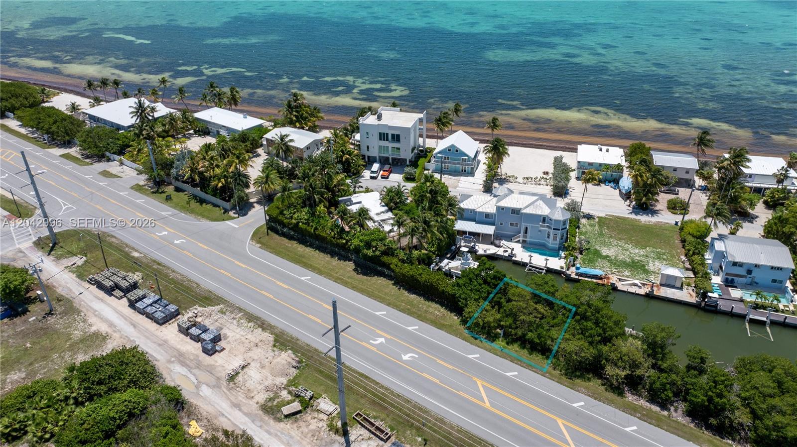 An aerial view shows a vacant, tree-covered lot outlined in blue next to a canal — 74051 Overseas Hwy, Islamorada FL 33036, ISLAMORADA, FL
