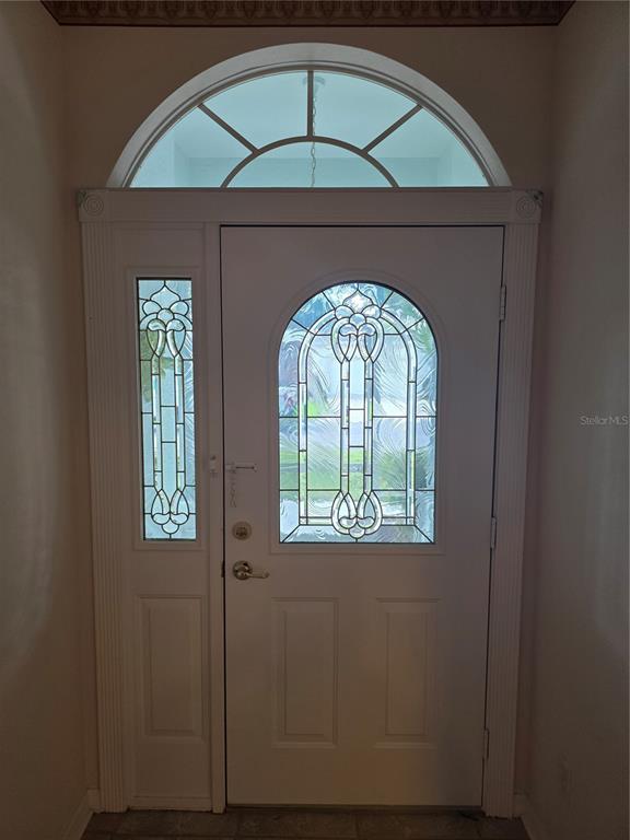 A white front door with decorative glass inserts, a sidelight, and an arched transom window — 2282 FENTON AVENUE, CLERMONT, FL