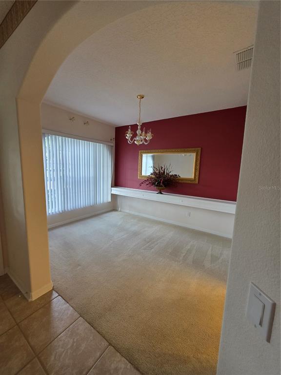 A dining room features a red accent wall, a long shelf, and a crystal chandelier — 2282 FENTON AVENUE, CLERMONT, FL