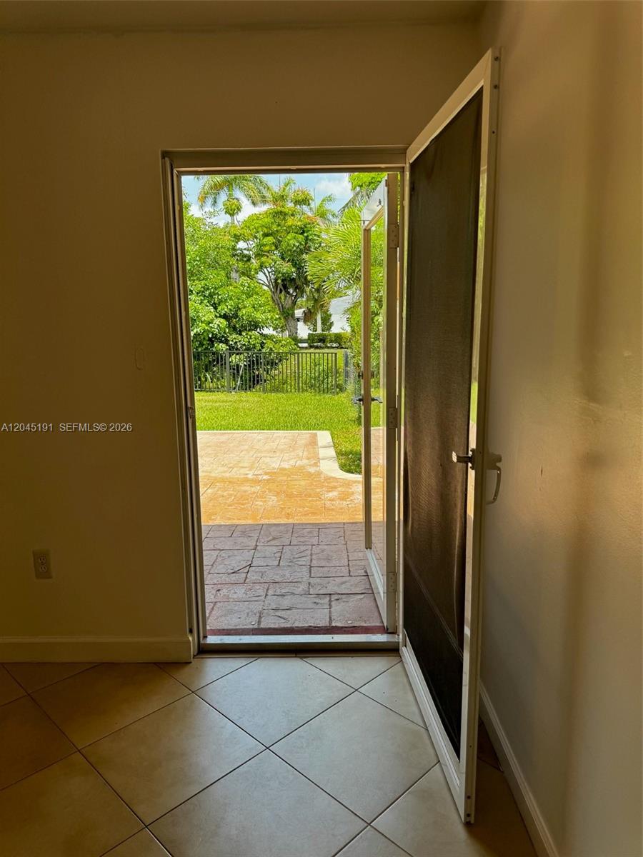 An open door leads from a tiled room to a backyard patio and green lawn — 158 SW 96th Ct # B, Miami FL 33174, MIAMI, FL