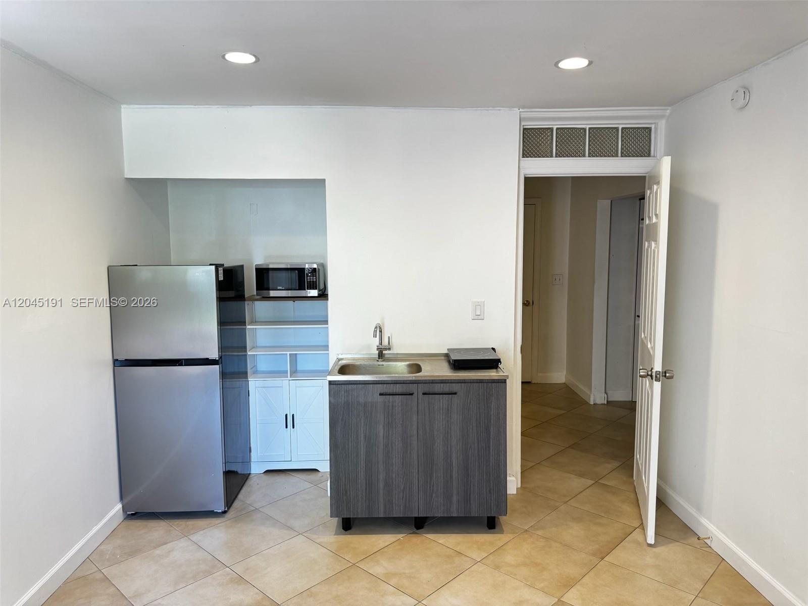 A small kitchenette features a stainless steel refrigerator, sink, and microwave in a tiled room — 158 SW 96th Ct # B, Miami FL 33174, MIAMI, FL