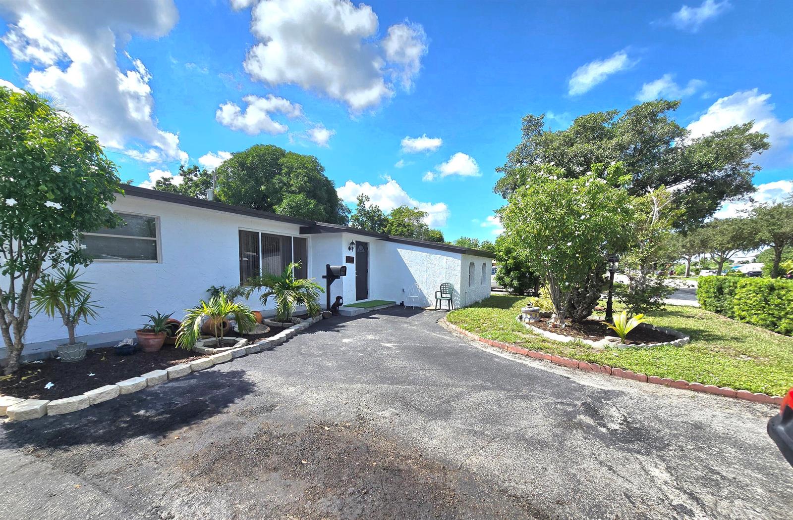 A white single-story house features a dark front door and an asphalt driveway — 6138 Southgate Boulevard, Margate FL 33068, MARGATE, FL