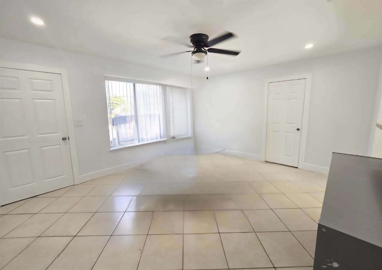 An empty room with white walls, tile flooring, a ceiling fan, and two white doors — 6138 Southgate Boulevard, Margate FL 33068, MARGATE, FL
