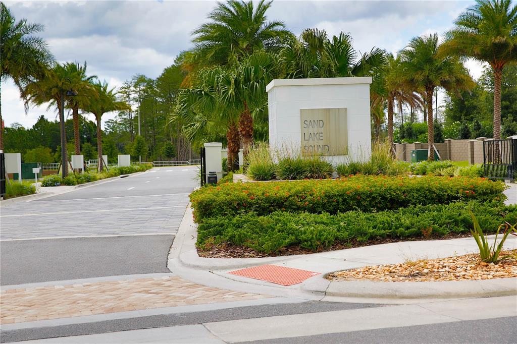 The entrance to the Sand Lake Sound community features a paved road and landscaping — 7389 ALPINE BUTTERFLY LANE, ORLANDO, FL