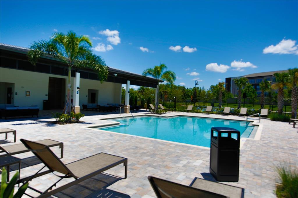 A swimming pool with lounge chairs on a paved deck next to a building — 7389 ALPINE BUTTERFLY LANE, ORLANDO, FL