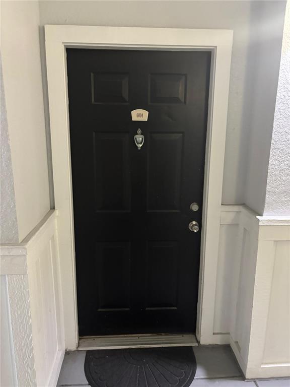 A black front door with a silver knocker and the number 6004 is framed in white — 300 E SOUTH STREET UNIT 6004, ORLANDO, FL