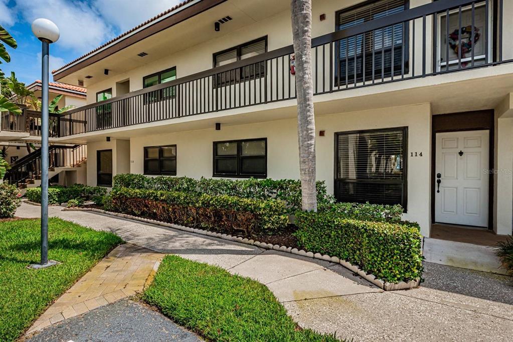 Exterior view of a two-story apartment building with a white facade and a walkway — 6294 BAHIA DEL MAR CIRCLE UNIT 114, ST PETERSBURG, FL