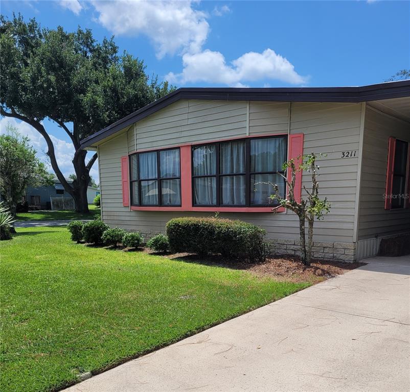A single-story house with light-colored siding, a bay window, and a concrete driveway — 3211 WEKIVA ROAD, TAVARES, FL