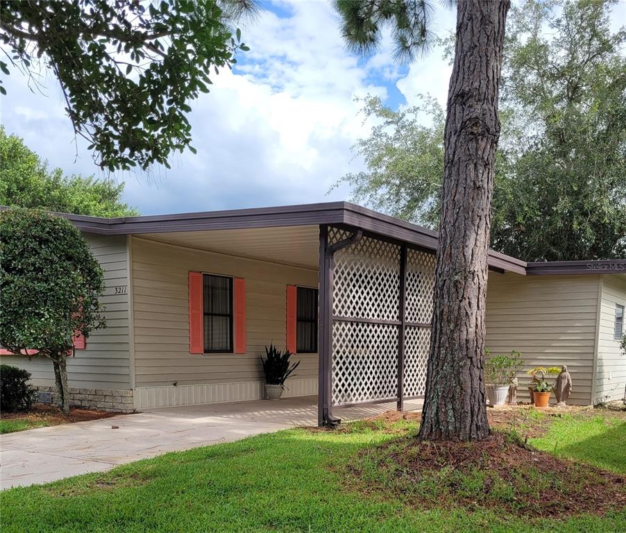 A single-story house with tan siding, a carport, and a white lattice privacy screen — 3211 WEKIVA ROAD, TAVARES, FL