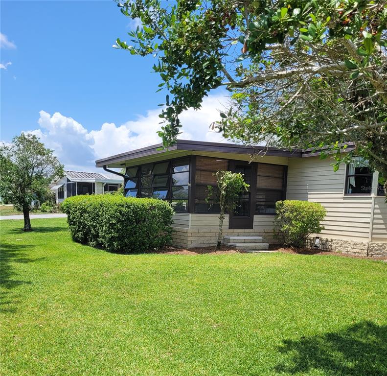 A single-story home with a screened-in porch, tan siding, and a brick foundation — 3211 WEKIVA ROAD, TAVARES, FL