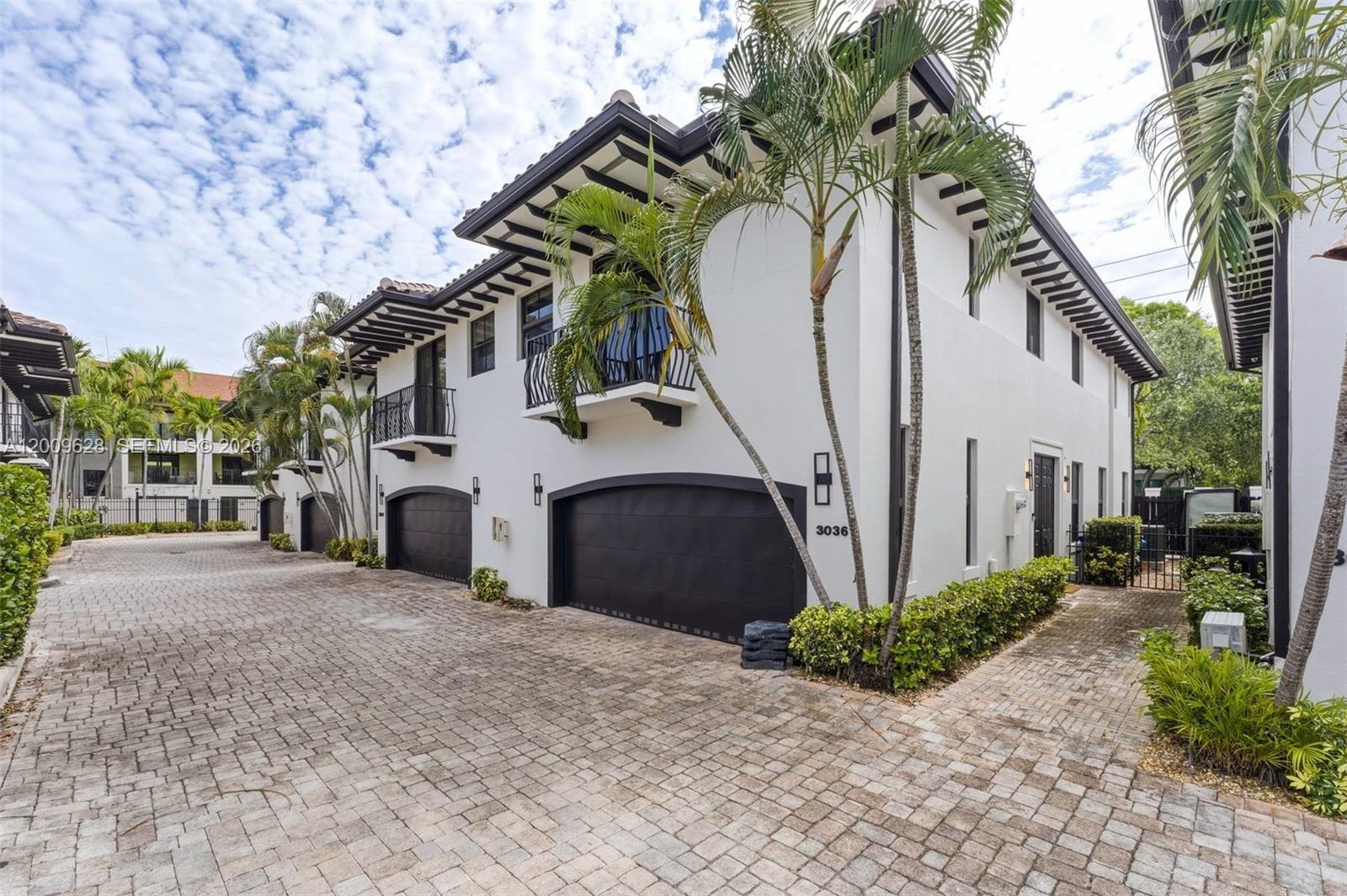 A two-story white townhouse with dark trim, a two-car garage, and palm trees — 3036 Mcdonald Street, Miami FL 33133, MIAMI, FL