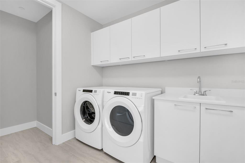 A laundry room features white cabinets, a sink, and a side-by-side washer and dryer — 275 1ST AVENUE S UNIT 2807, ST PETERSBURG, FL