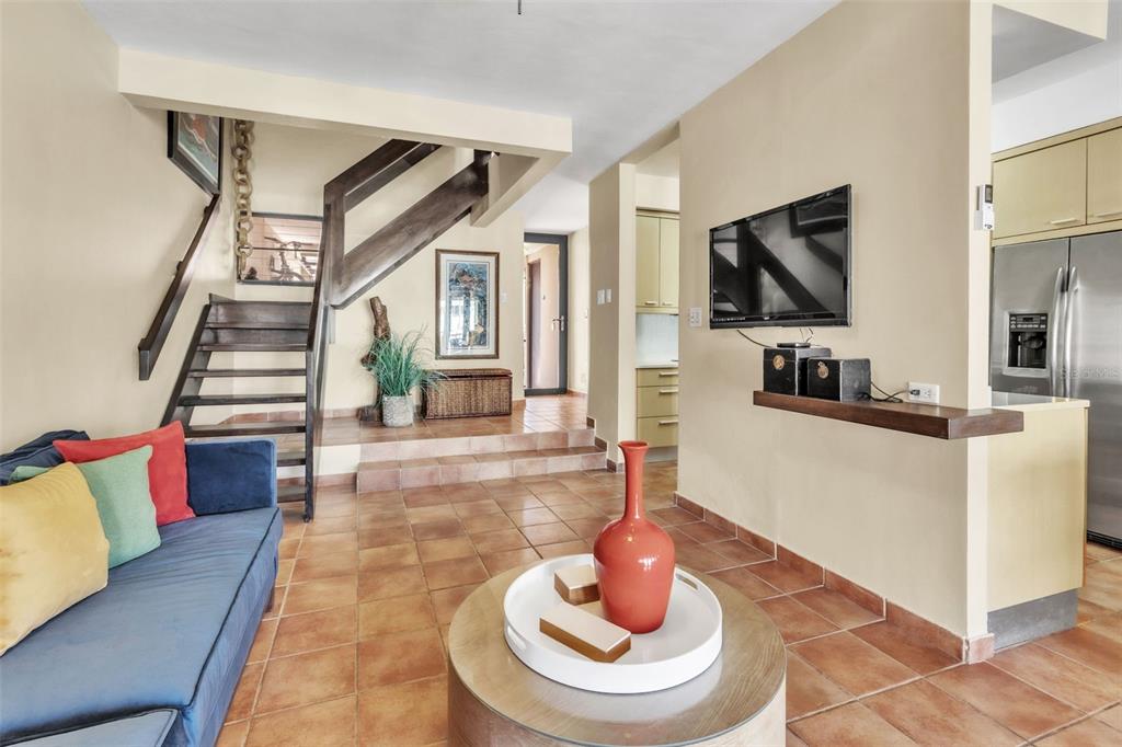 A living room features a blue sofa, tiled floors, a staircase, and a wall-mounted television — 7 ISLA SAN MARCOS UNIT 7, HUMACAO, PR