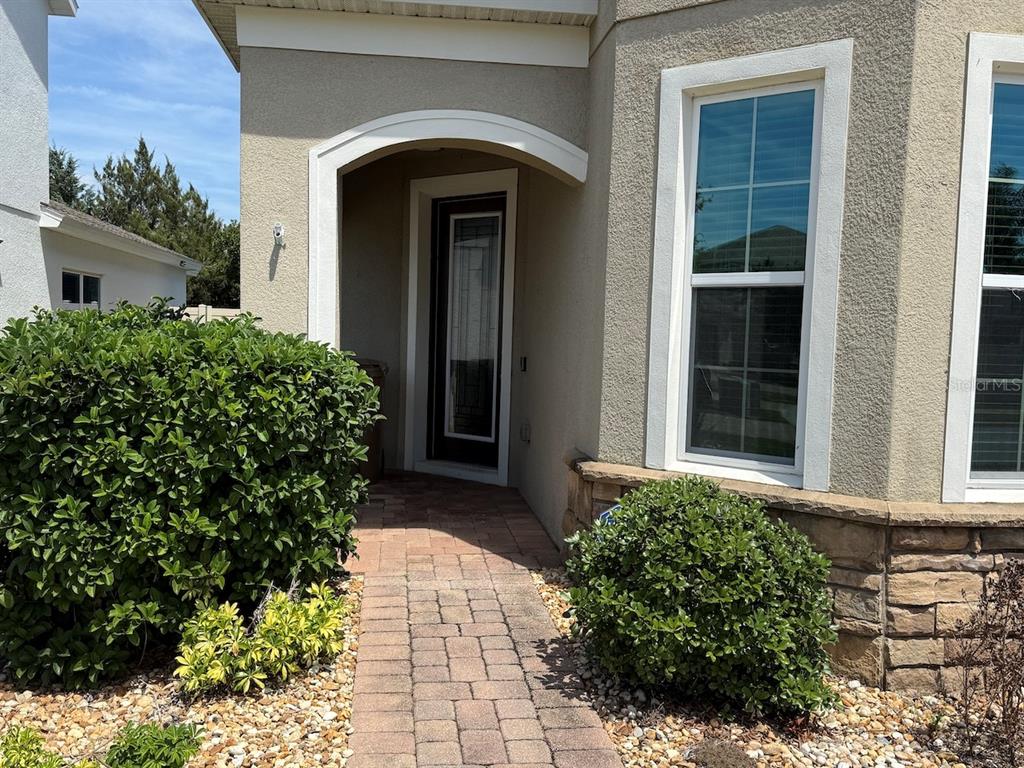 A paved walkway leads to the front entrance of a house with beige stucco siding — 5251 VILLA ROSA AVENUE, ST CLOUD, FL