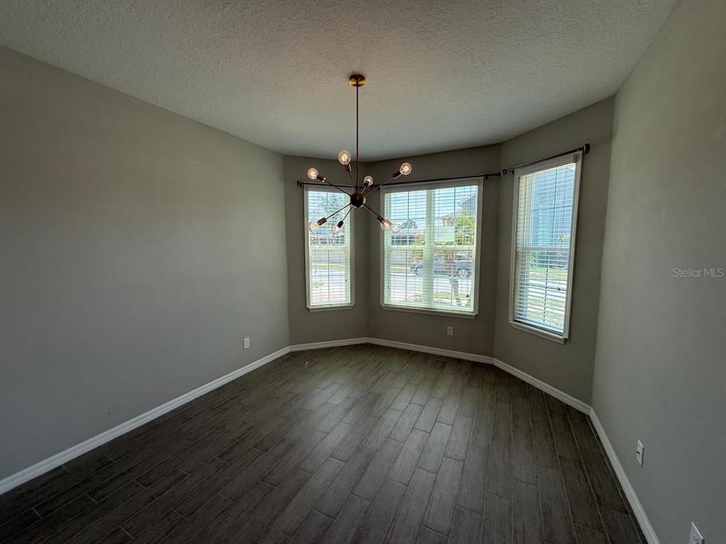 A dining room features gray walls, wood-look tile flooring, and a modern sputnik chandelier — 5251 VILLA ROSA AVENUE, ST CLOUD, FL