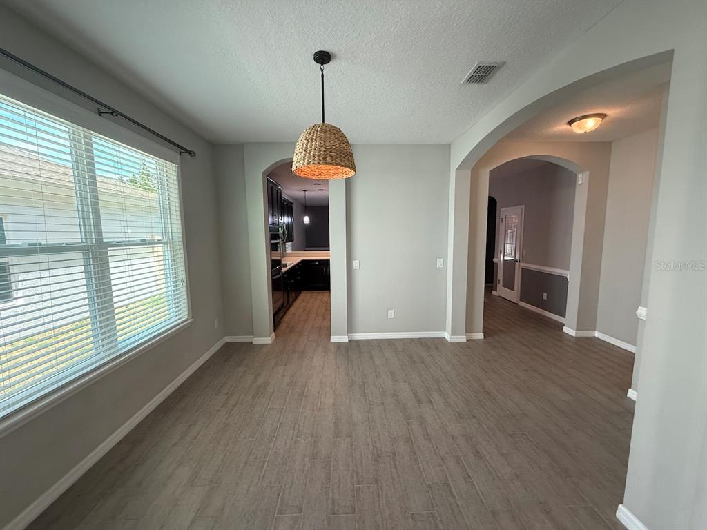 A dining area with wood-look tile flooring, a woven pendant light, and arched doorways — 5251 VILLA ROSA AVENUE, ST CLOUD, FL