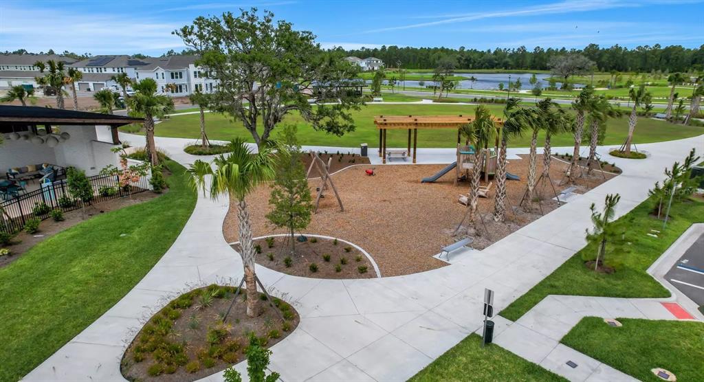 An aerial view of a neighborhood playground with a wooden pergola, swings, and a slide — 2984 GARDEN TRAIL BEND, ST CLOUD, FL
