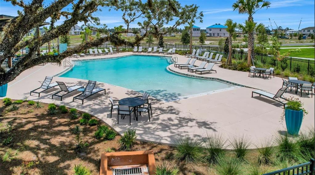 An outdoor swimming pool with lounge chairs and patio tables surrounded by landscaping — 2984 GARDEN TRAIL BEND, ST CLOUD, FL