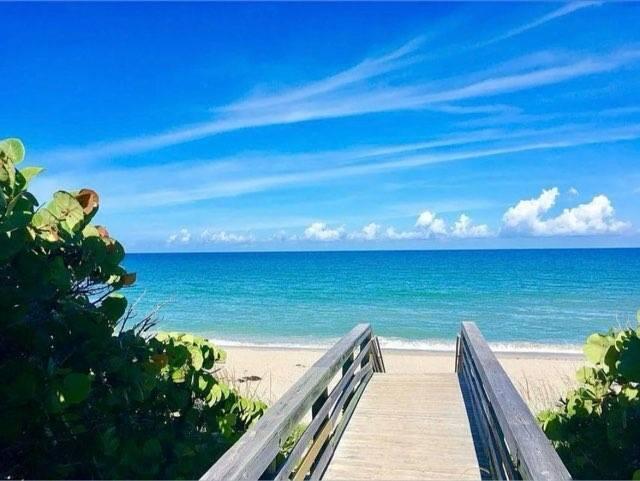 A wooden boardwalk leads through green foliage to a sandy beach and the blue ocean — 602 Mainsail Circle, Jupiter FL 33477, JUPITER, FL