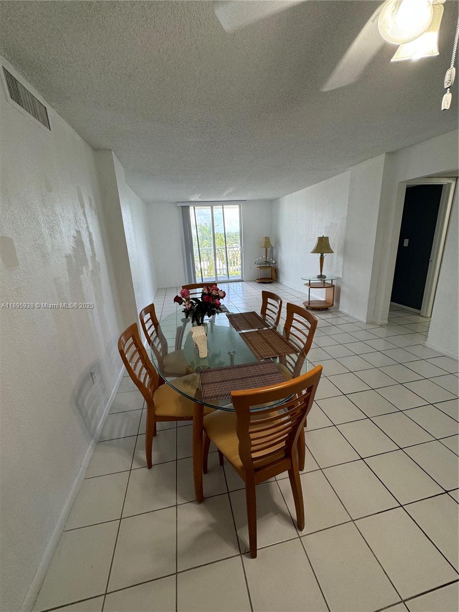 A dining area features a glass-topped table with six wooden chairs on tiled floors — 1251 NE 108th St # 602, Miami FL 33161, MIAMI, FL
