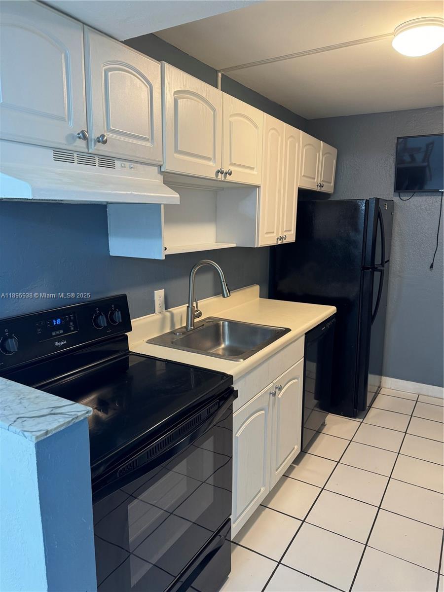 A kitchen features white cabinets, black appliances, a stainless steel sink, and white tile flooring — 1251 NE 108th St # 602, Miami FL 33161, MIAMI, FL