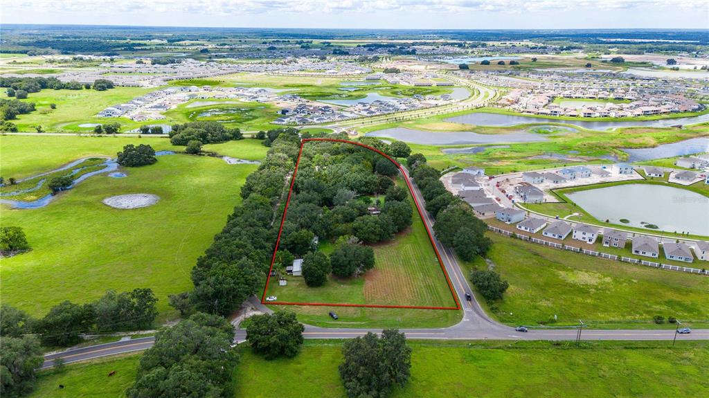 An aerial view shows a rectangular plot of land outlined in red near a residential development — 32551 LEONARD ROAD, SAN ANTONIO, FL