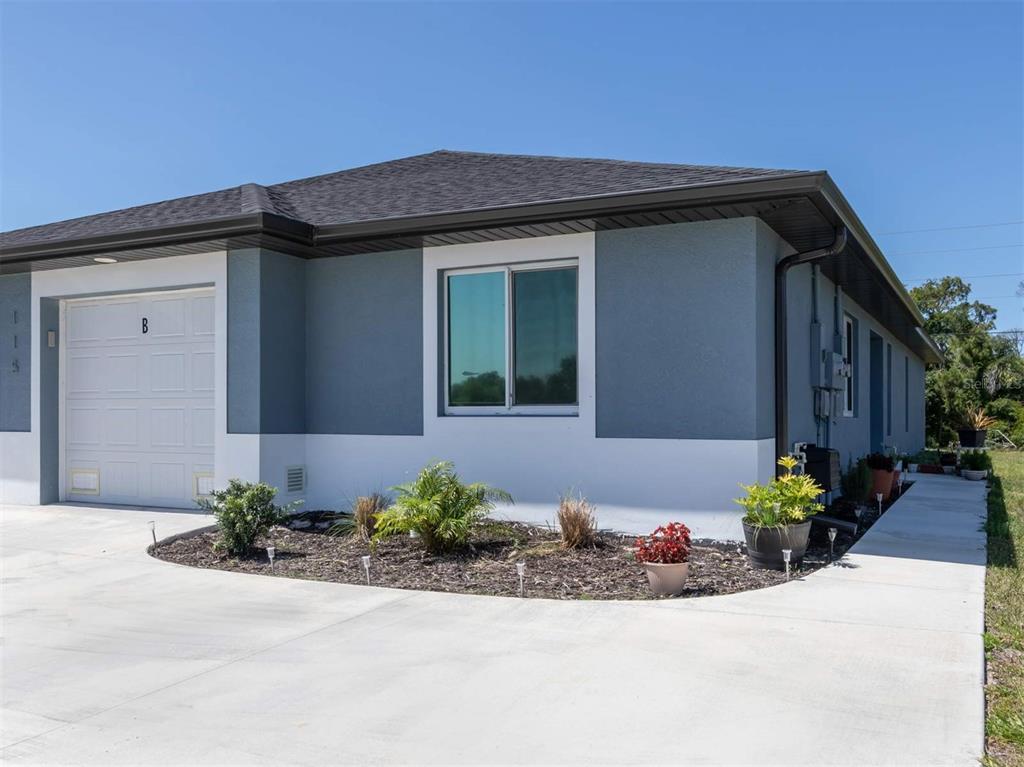 A single-story house exterior with a white garage, gray walls, and a concrete driveway — 125 BOUNDARY BOULEVARD UNIT 2, ROTONDA WEST, FL