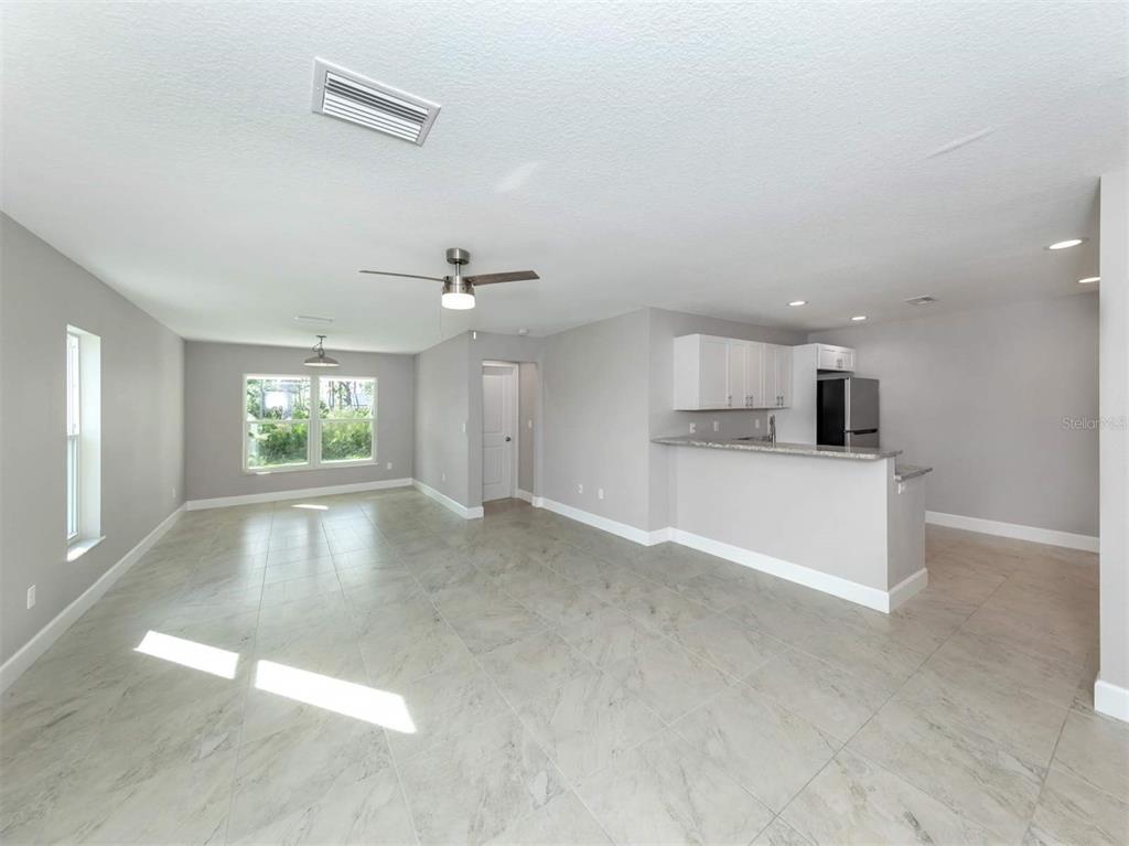 An open-concept living and kitchen area features light gray walls, tile flooring, and white cabinetry — 125 BOUNDARY BOULEVARD UNIT 2, ROTONDA WEST, FL