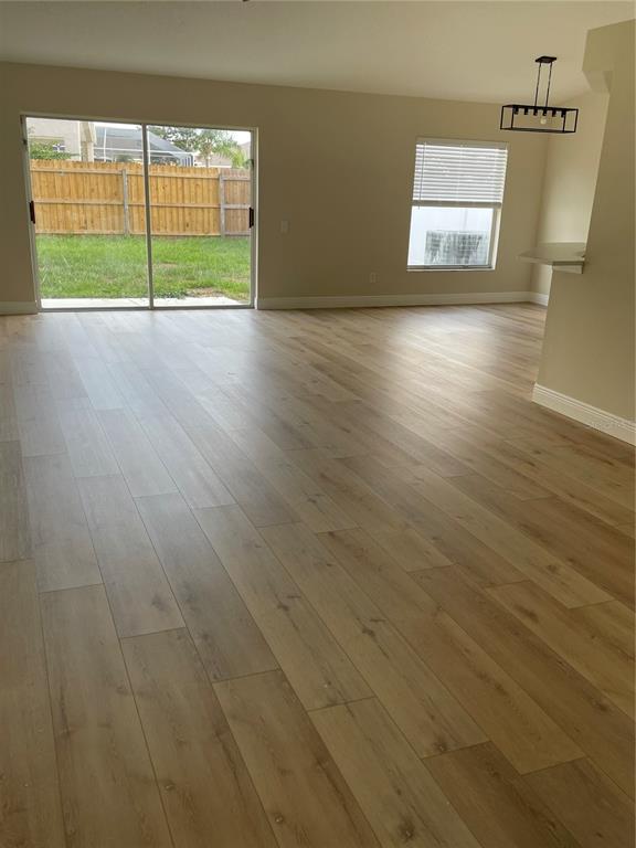 A living area with light wood-look flooring, a sliding glass door, and a window — 10467 HALLMARK BOULEVARD, RIVERVIEW, FL