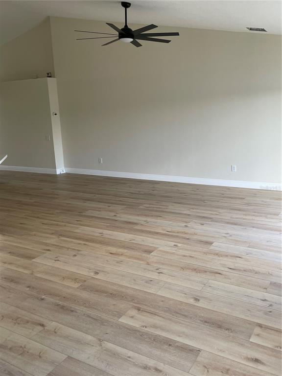 A spacious room features light wood-look flooring, beige walls, and a black ceiling fan — 10467 HALLMARK BOULEVARD, RIVERVIEW, FL