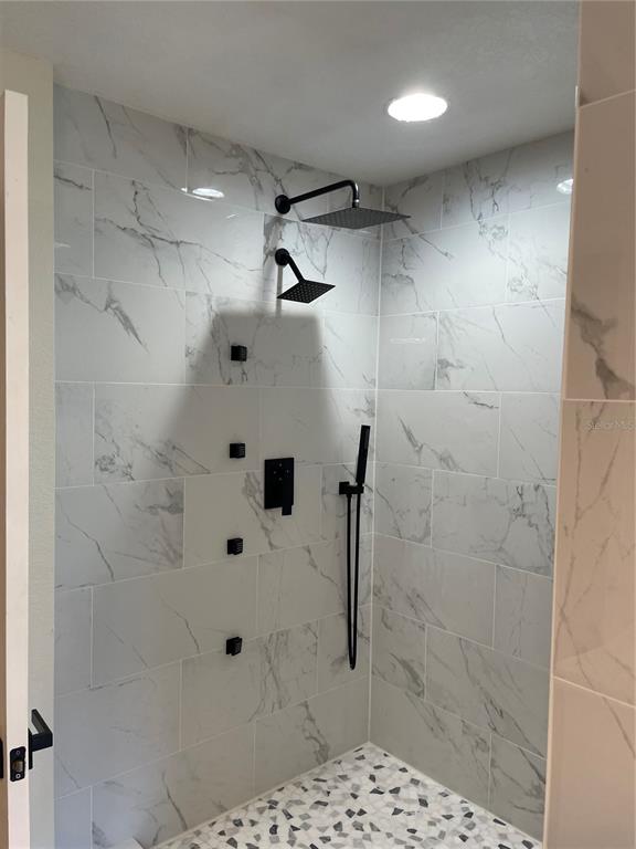 A walk-in shower features marble-look wall tiles, a mosaic floor, and matte black fixtures — 10467 HALLMARK BOULEVARD, RIVERVIEW, FL