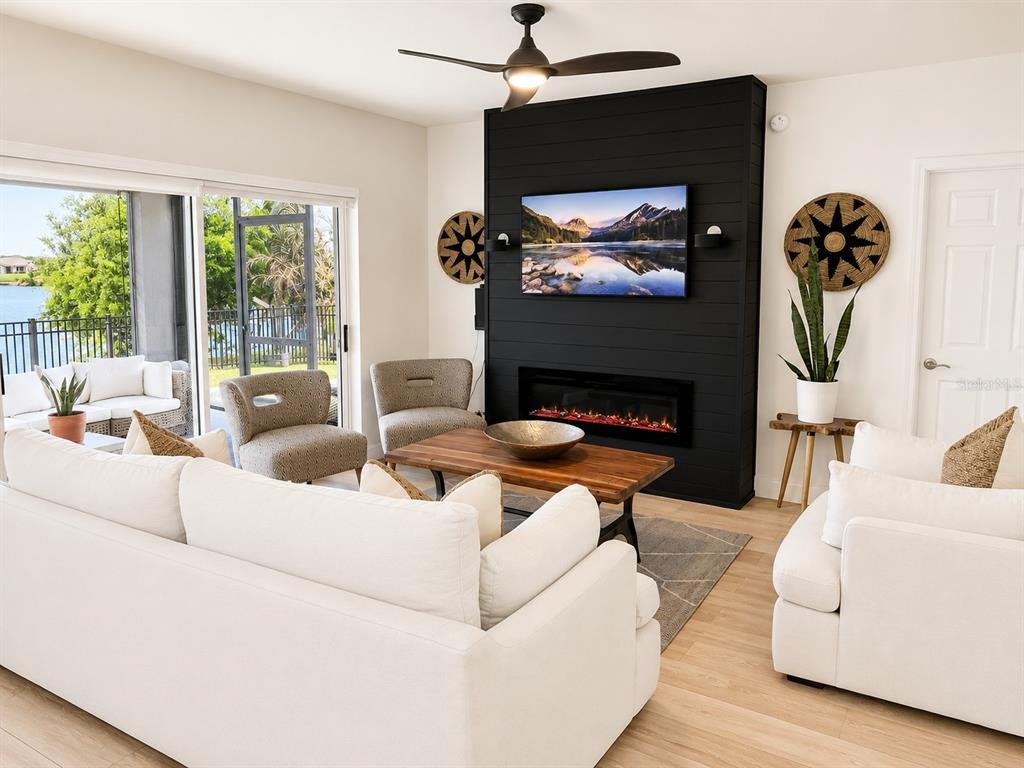 A living room features a black shiplap fireplace wall, white sofas, and sliding glass doors — 5267 WHITE EGRET LANE, LAKELAND, FL