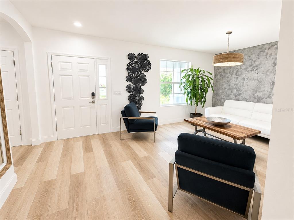 A living room features light wood floors, a white sofa, two dark armchairs, and textured wallpaper — 5267 WHITE EGRET LANE, LAKELAND, FL