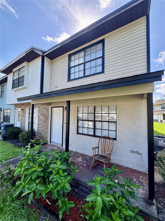 A two-story house exterior features a covered porch, a wooden rocking chair, and light siding — 1415 RIDGE LAKE COURT, LAKELAND, FL