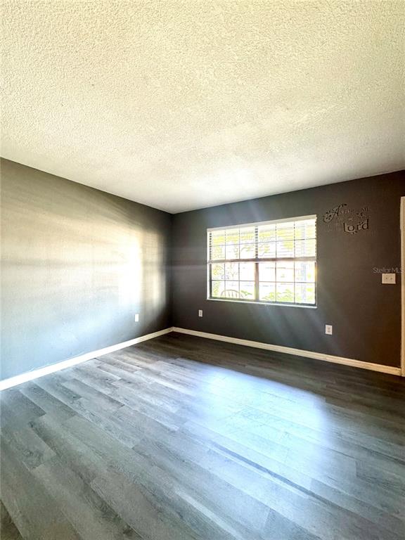 An empty room features dark gray walls, wood-look flooring, and a single window — 1415 RIDGE LAKE COURT, LAKELAND, FL