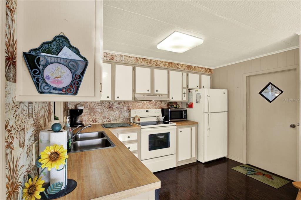 A kitchen features wood-look laminate countertops, white appliances, and patterned wallpaper — 14294 BROOKRIDGE BOULEVARD, BROOKSVILLE, FL