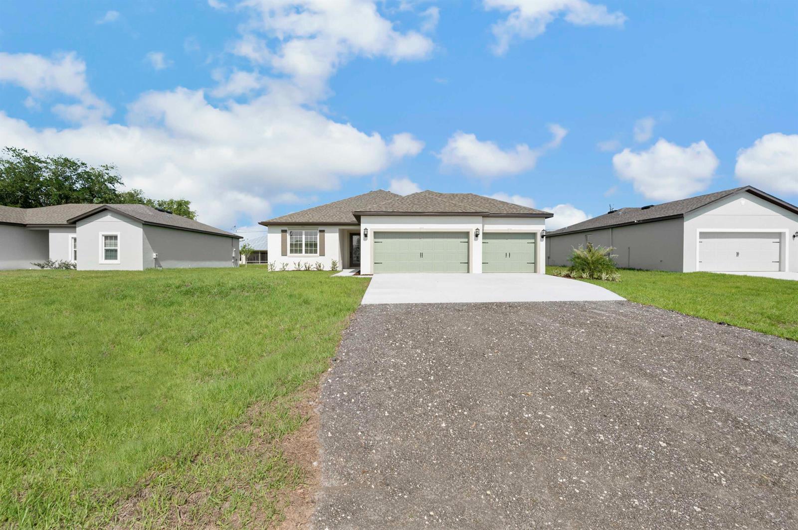 A single-story house with a two-car garage and a paved driveway under a blue sky — 9335 101st Avenue, Vero Beach FL 32967, VERO BEACH, FL