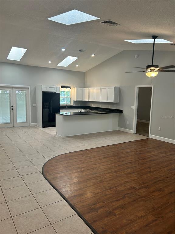 A kitchen with white cabinets and black countertops opens to a living area with skylights — 1181 ANNE ELISA CIRCLE, ST CLOUD, FL
