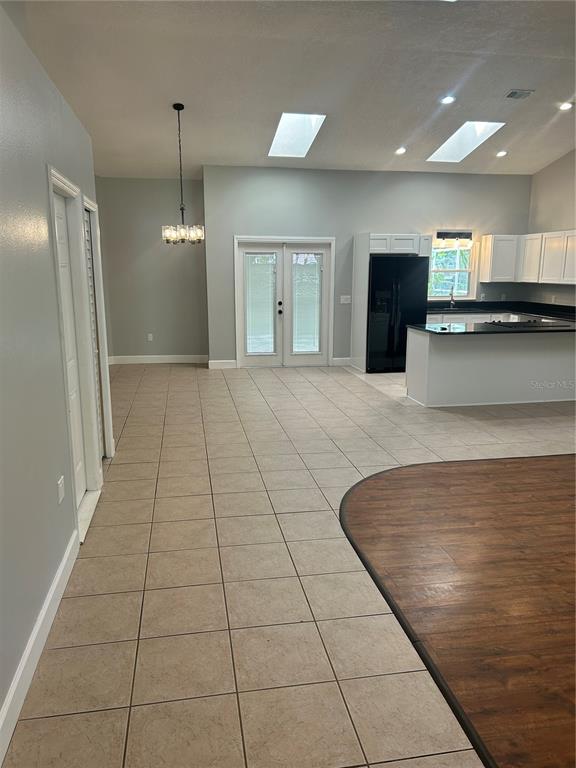 A kitchen and dining area feature tile flooring, white cabinets, a black refrigerator, and skylights — 1181 ANNE ELISA CIRCLE, ST CLOUD, FL