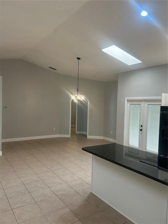 A kitchen with a black countertop overlooks a dining area with a vaulted ceiling — 1181 ANNE ELISA CIRCLE, ST CLOUD, FL