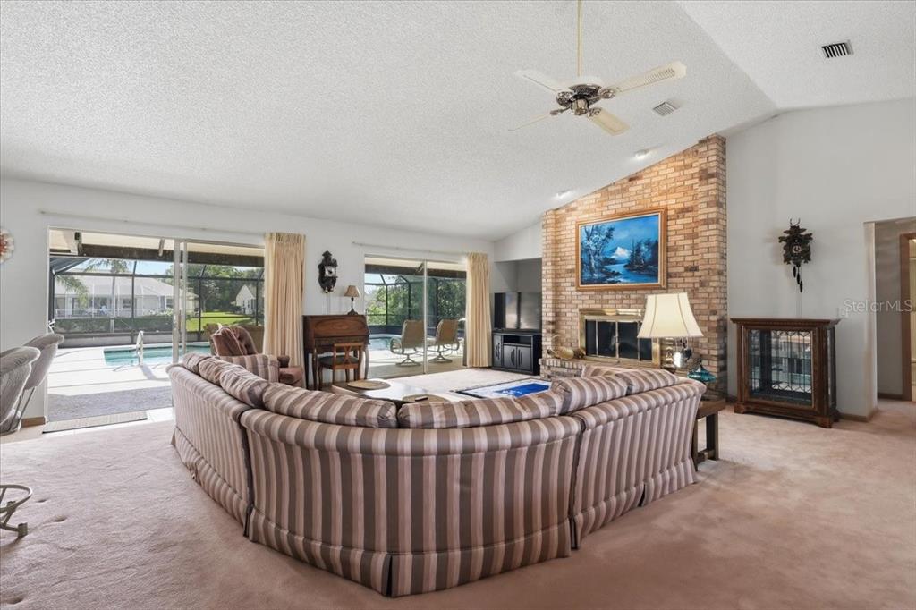 A living room features a large sectional sofa, a brick fireplace, and sliding glass doors — 23 CHRISTOPHER COURT, PALM COAST, FL