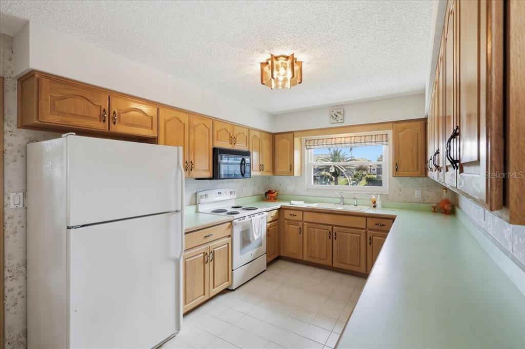 A kitchen with light wood cabinets, green countertops, white appliances, and a window over the sink — 23 CHRISTOPHER COURT, PALM COAST, FL
