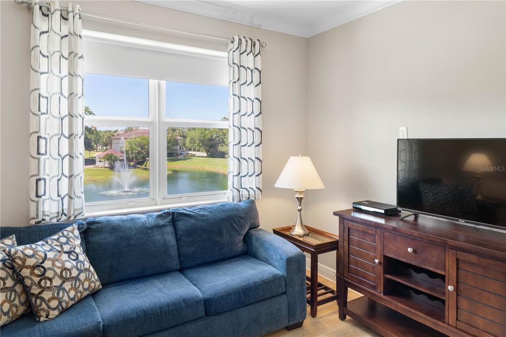 A living room features a blue sofa, a television on a wooden console, and a window — 80 RIVERVIEW BEND S UNIT 821, PALM COAST, FL