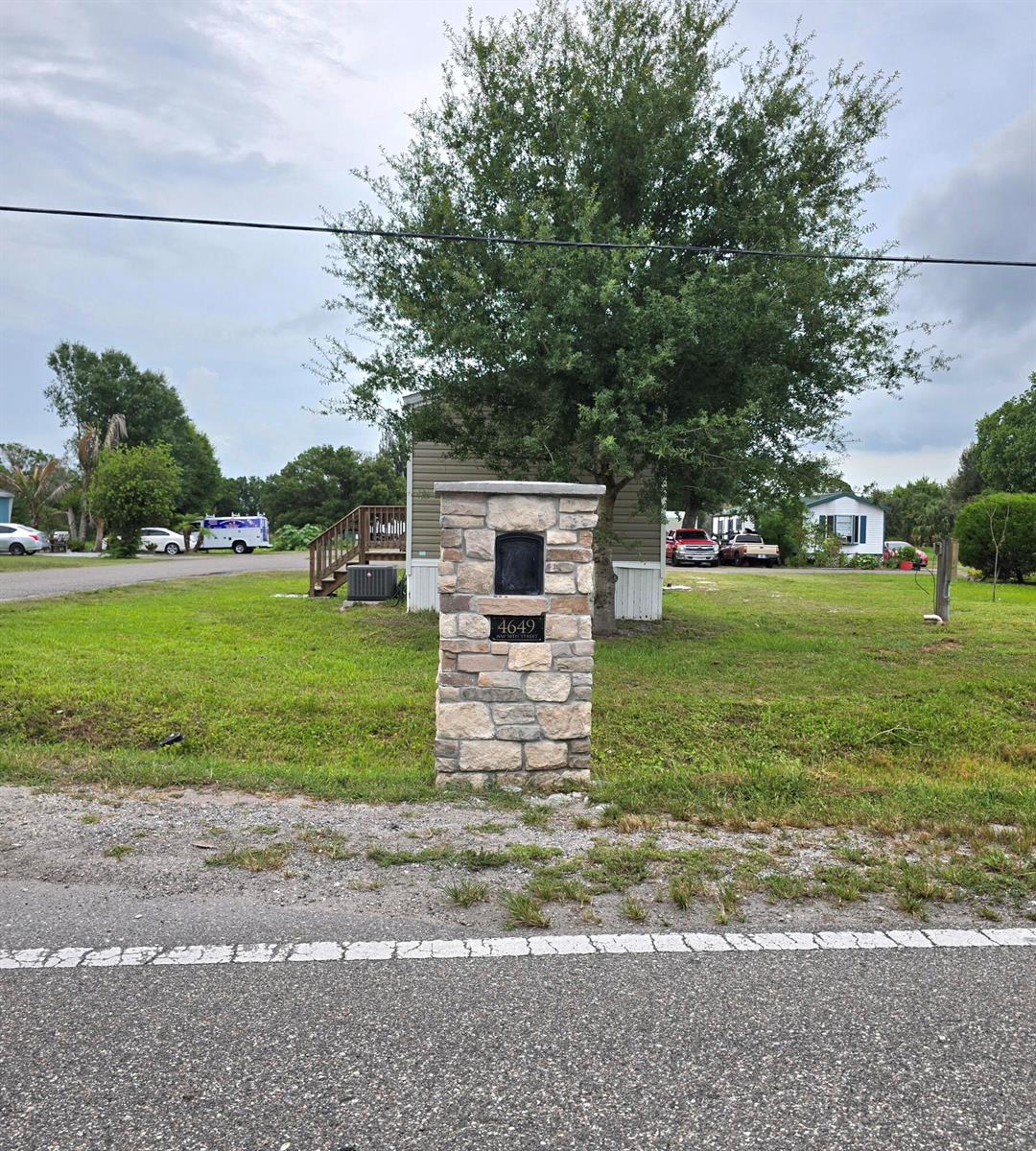 A stone mailbox pillar stands in a grassy yard in front of a mobile home — 4649 NW 30th Street, Okeechobee FL 34972, OKEECHOBEE, FL